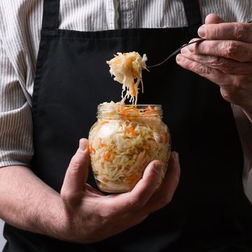 a man in an apron holding a fermented cabbage