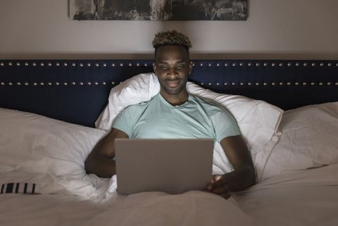 man in bed on lap top computer