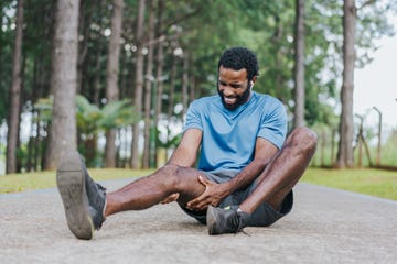 man zit op de grond met pijn aan hamstring