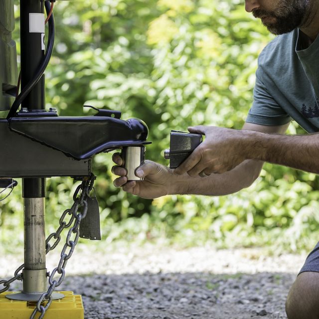 man installing camper trailer padlock during camping in summer