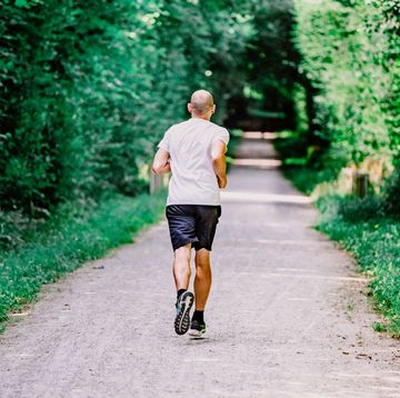 a man is running on a path surrounded by greenery.