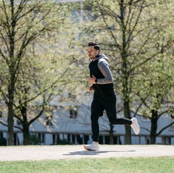 man jogging in a public park in an urban city surrounding wearing a smart watch and wireless in ear headphones