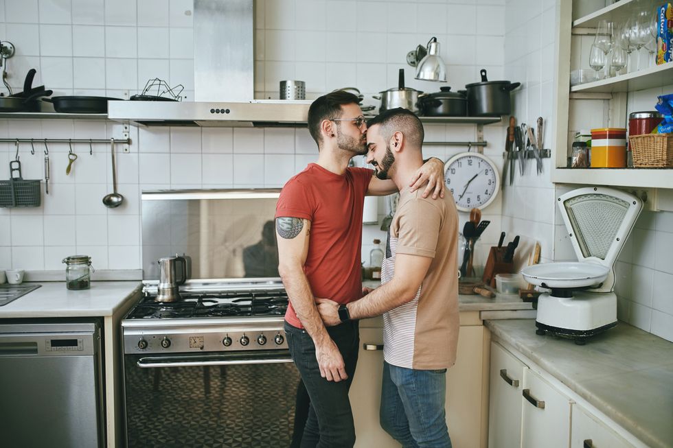 hombre besando a su novio en la cocina