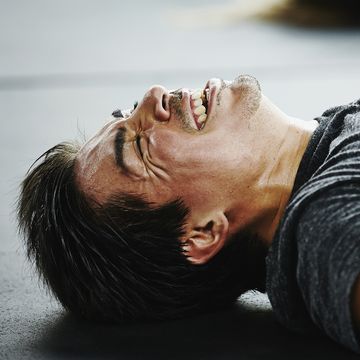 Man laughing and grimacing lying on floor of gym