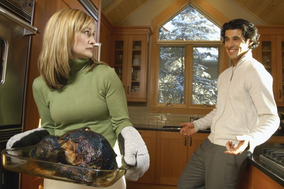 man laughing at woman holding burnt turkey