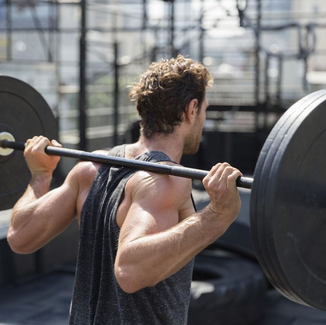 man lifting barbell exercising at rooftop gym