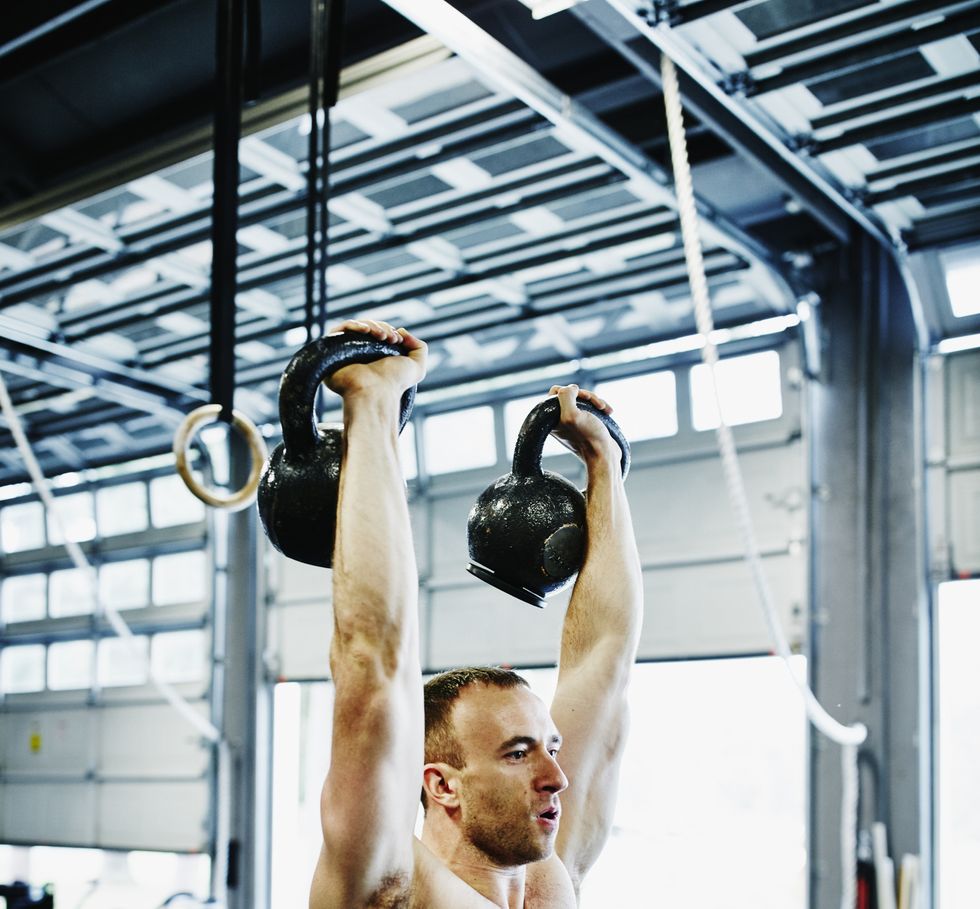 Man lifting kettlebells above head during workout
