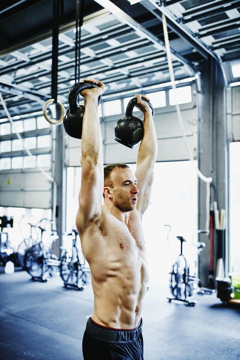 Man lifting kettlebells above head during workout