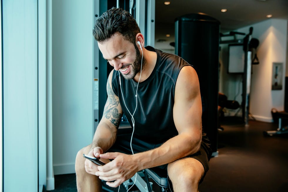 man listening to earbuds in gymnasium