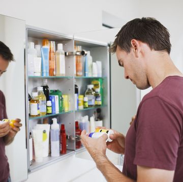 man looking at bottles from medicine cabinet