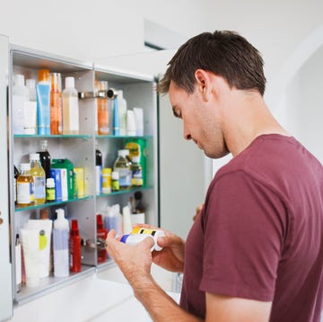 man looking at bottles from medicine cabinet