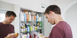 man looking at bottles from medicine cabinet