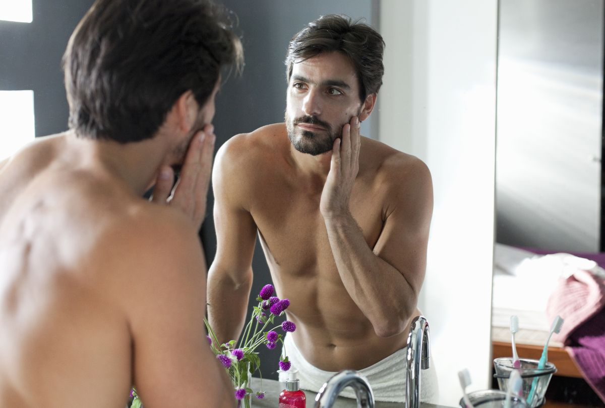 man looking at himself in bathroom mirror