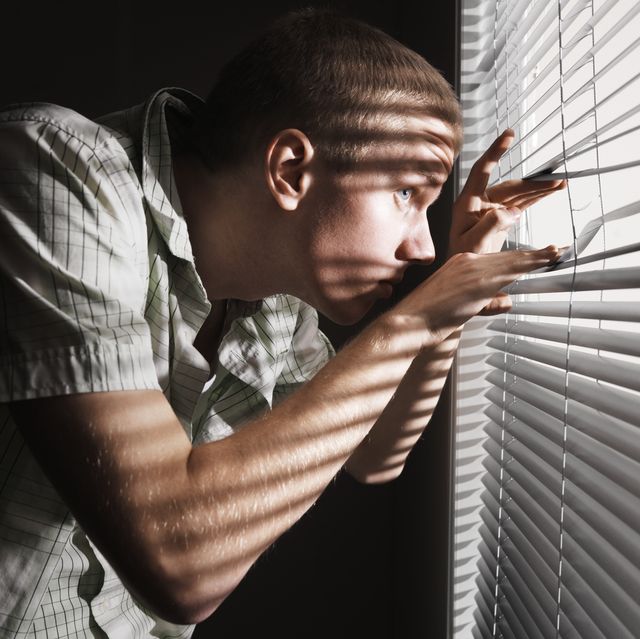 man looking through the blinds