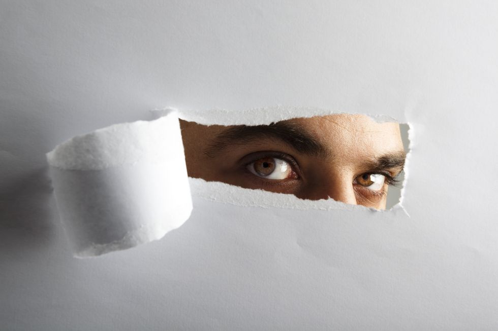 man looking through torn paper