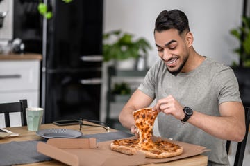 man looking with delight at pizza taking slice