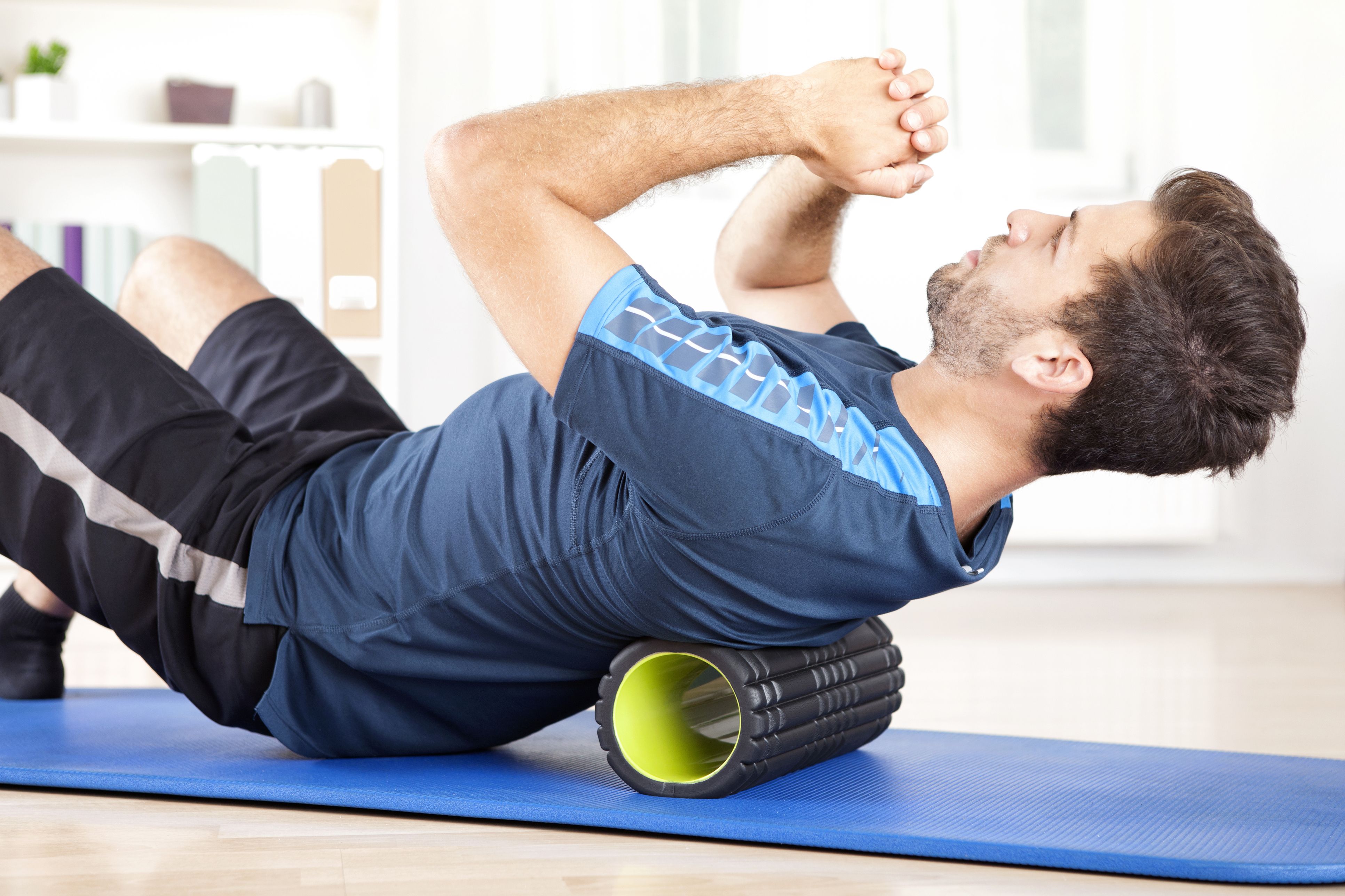 https://hips.hearstapps.com/hmg-prod/images/man-lying-on-a-foam-roller-while-doing-an-exercise-royalty-free-image-509421384-1545148853.jpg