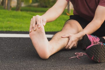 man massaging his painful foot from jogging on track