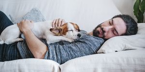 man napping with dog while lying on sofa at home, take a week off from exercise