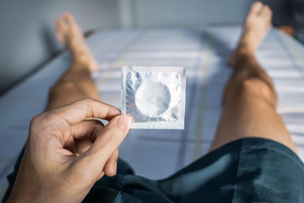 man on bed holding condom package