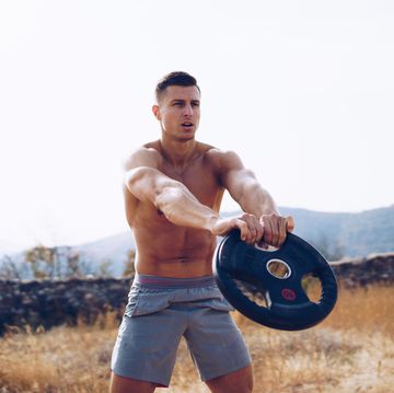 young muscular man excercise with barbell outdoors