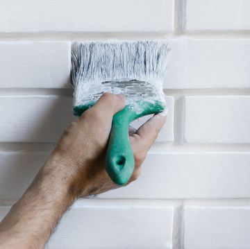 Man painting with brush brick wall on white color