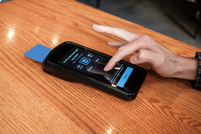 man pays bill at restaurant with credit card on wireless device