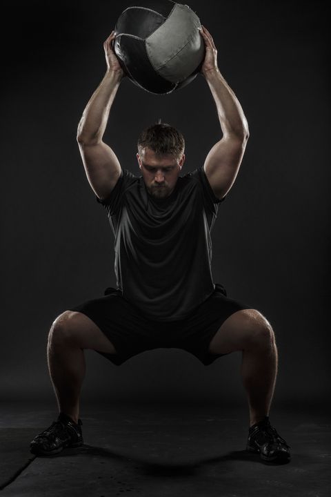 A man performing a medicine ball squat