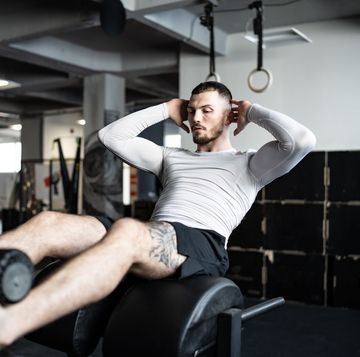 man performing abdominal exercise on gym equipment during workout