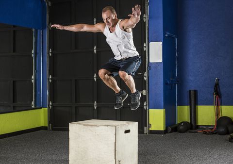 Man performing box jump in gym