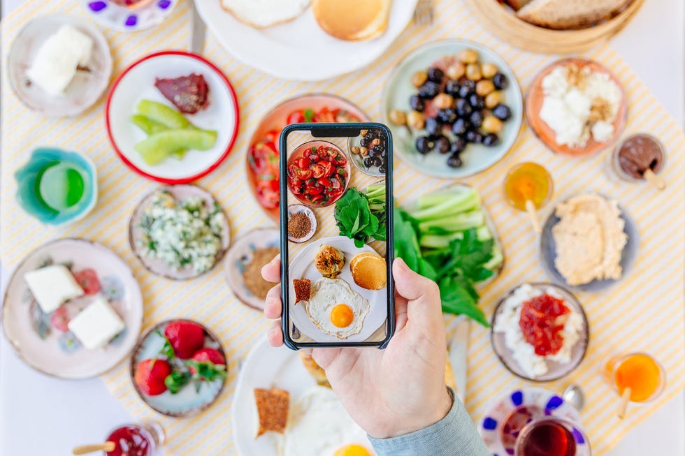 man photographing table with traditional turkish breakfast in a restaurant, personal perspective