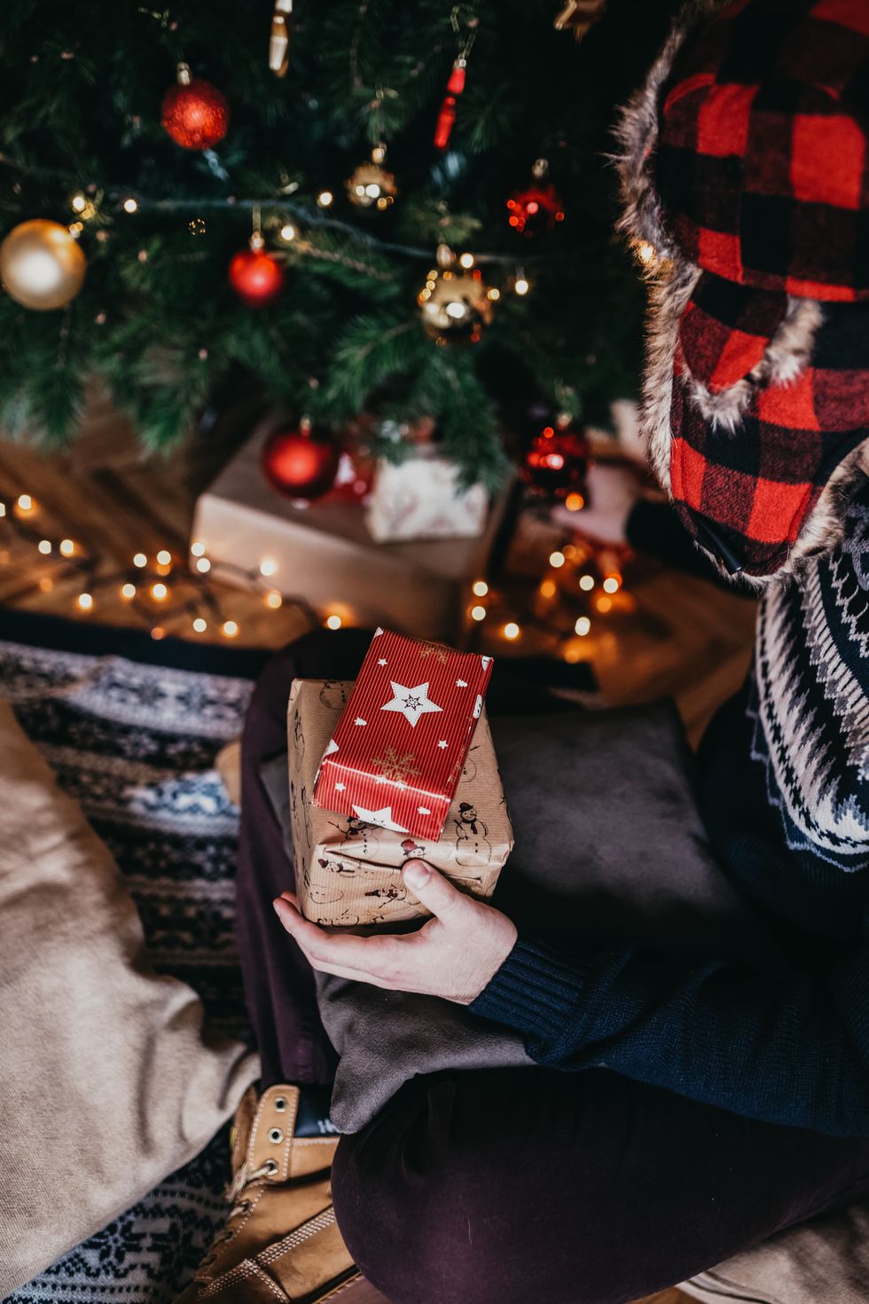 Man placing Christmas present, under Christmas tree.