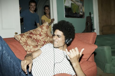 man playing air guitar with friends watching