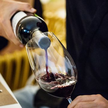 man pouring red wine in glass during dinner party