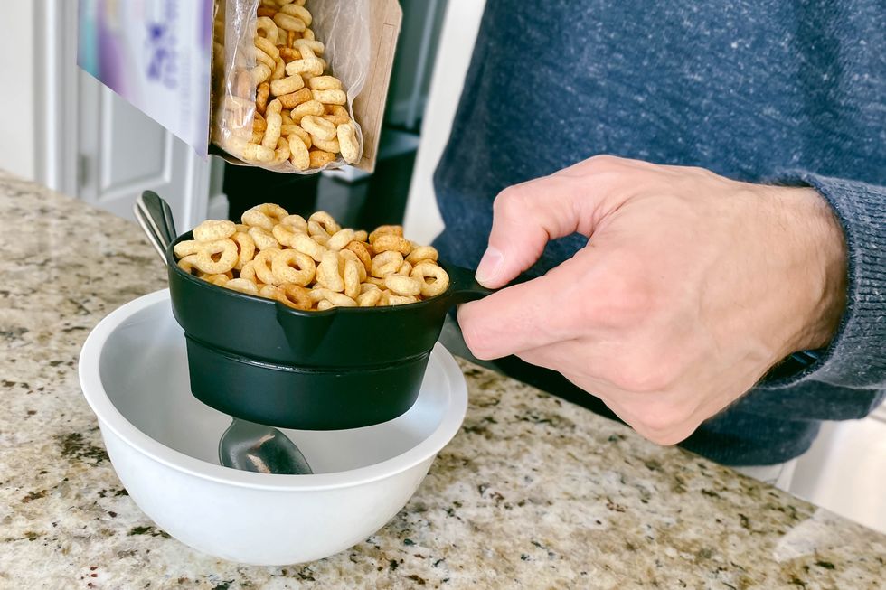 man pours breakfast cereal into measuring cup