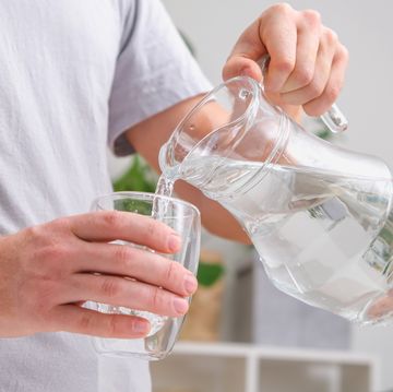 man pours cold water into glass close up of male hands pouring water from a jug into glass tumbler