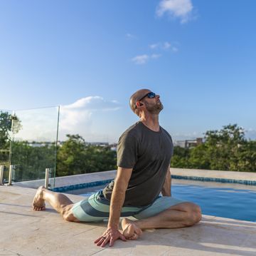 man practices yoga at poolside, while on holiday