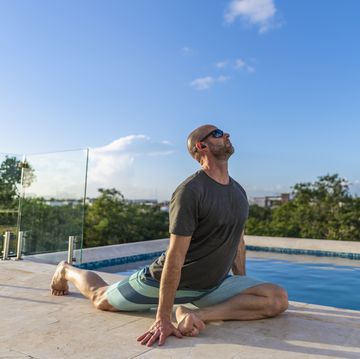 man practices yoga at poolside, while on holiday