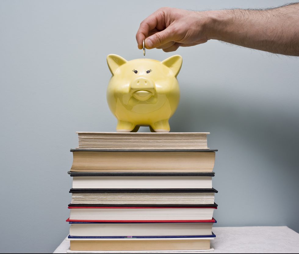 man puts coin in piggy bank saving money for school
