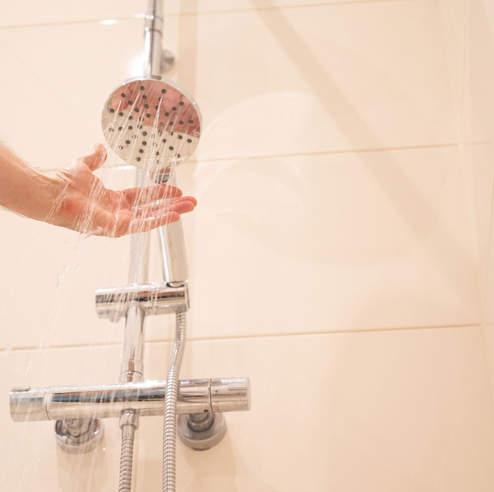 a man puts his arm under the shower water