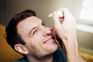 man putting eye drops