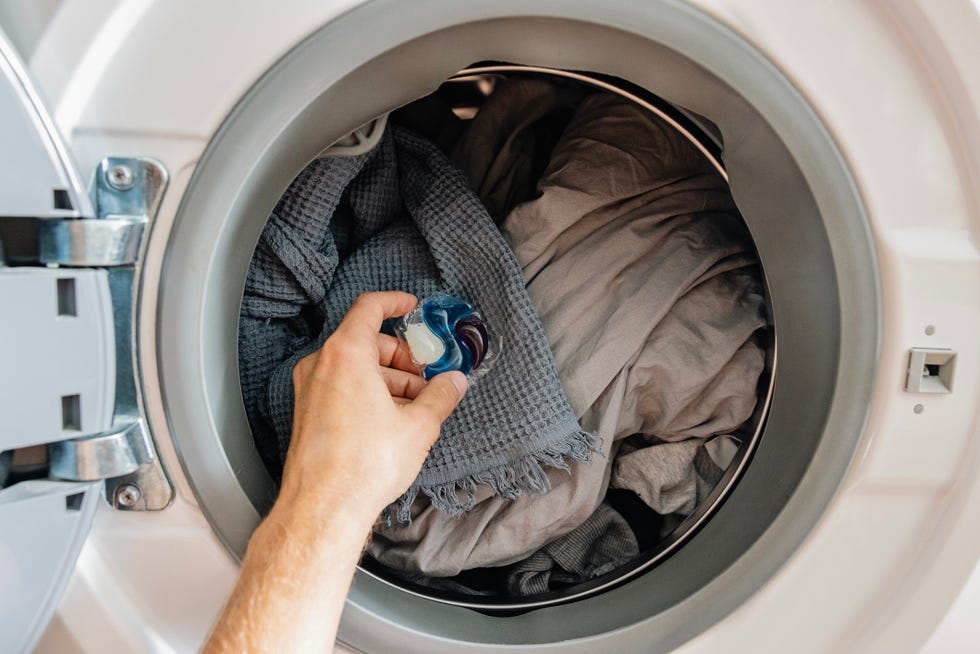 man putting liquid laundry detergent pod in washing machine