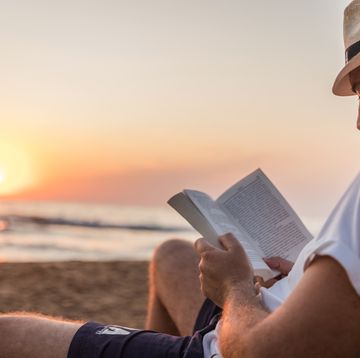 man reading a book at the beach