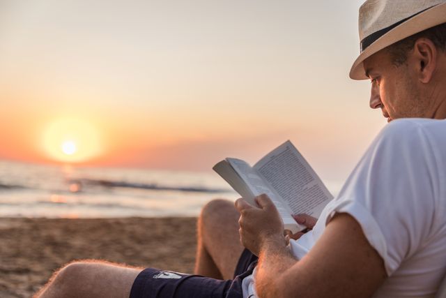man reading a book at the beach