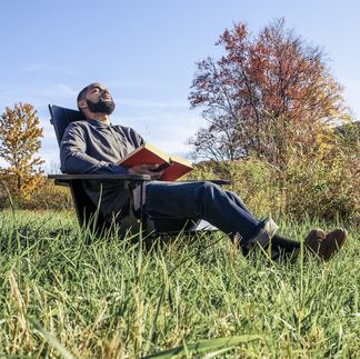 man relaxing in chair at grassy field