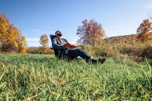 man relaxing in chair at grassy field