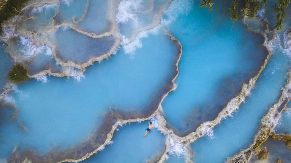 man relaxing in natural hot springs, tuscany, italy