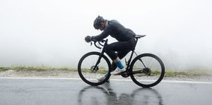 man relaxing on bicycle at wet street in foggy weather