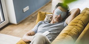 man relaxing on sofa wearing eye mask at home