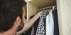 man removing clothes from closet at home